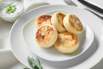 Plate with tasty cottage cheese pancakes and sauce on table, closeup