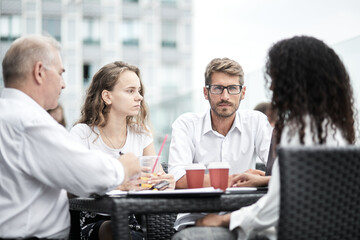 Smiling colleagues working together developing business strategy for their next project. Young casually dressed business people having discussion on sunny terrace. Modern job in comfortable conditions