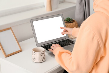 Woman pointing at blank laptop screen in room