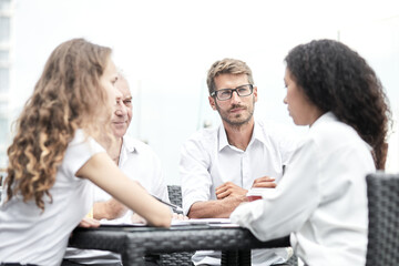 Smiling colleagues working together developing business strategy for their next project. Young casually dressed business people having discussion on sunny terrace. Modern job in comfortable conditions