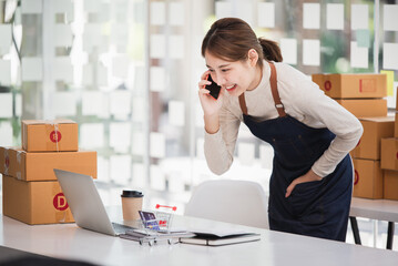 Obraz premium Small start-up business owners using computers and phones at work, salespeople, checking production orders. Pack products to ship to customers, sell ecommerce shipping ideas.