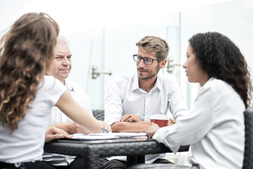 Obraz premium Smiling colleagues working together developing business strategy for their next project. Young casually dressed business people having discussion on sunny terrace. Modern job in comfortable conditions