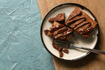 Plate with pieces of tasty chocolate brownie on blue background