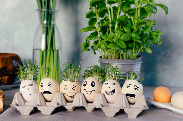 Funny easter eggs with expression face with cress on the easter table with herbal and cake. Food...