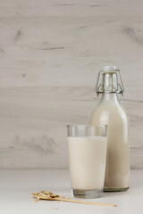A bottle and a glass with alternative dairy free almond milk on light background. Lactose free beverage