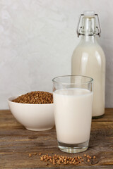 A bottle and a glass with alternative dairy free buckweat milk and seeds in a bowl. Lactose free beverage