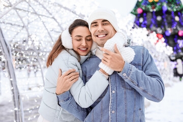 Pair of sweethearts hugging on snowy winter day