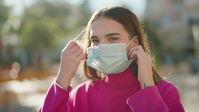 Young blonde woman smiling confident wearing medical mask at park