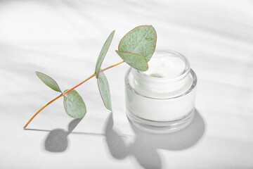 Jar with natural cosmetic cream and eucalyptus branch on white background © Pixel-Shot