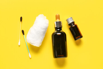 Medical cotton wool, swab and bottles with iodine on yellow background
