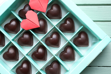 Box with tasty heart-shaped candies on color wooden background, closeup
