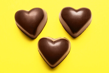 Tasty heart-shaped candies on yellow background