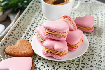 Plate with tasty heart-shaped macaroons on table