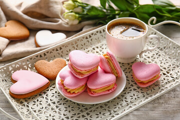 Tray with tasty heart-shaped macaroons and cup of coffee on table