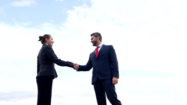 Happy woman and man business partners shake hands on sky, partnership