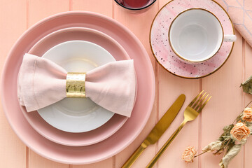 Beautiful table setting with flowers on pink wooden background