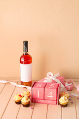 Calendar with date of Valentines Day and tasty cupcakes on pink wooden background