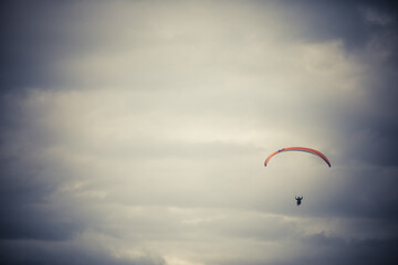 Paraglider flying alone, against a cloudy sky