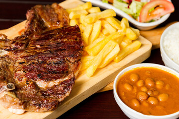 variety of meats with french fries, salad and rice with vegetable stew