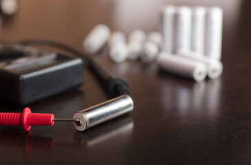 battery, volt meter, red positive pole, black negative pole, on work table.