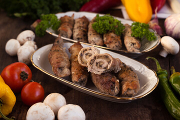 Pork rolls with mushrooms, meat rolls surrounded by greenery and vegetables. Ukrainian dishes is called krucheniki