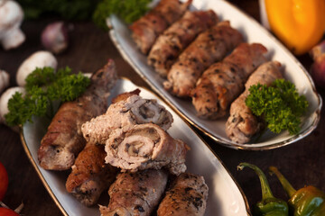 Pork rolls with mushrooms, meat rolls surrounded by greenery and vegetables. Ukrainian dishes is called krucheniki