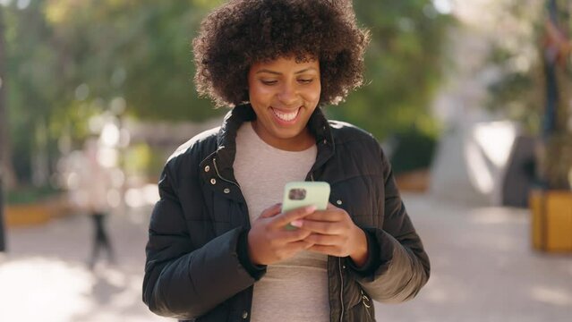 Young african american woman smiling confident using smartphone at park