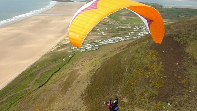 Following a paraglider above coastal scenery