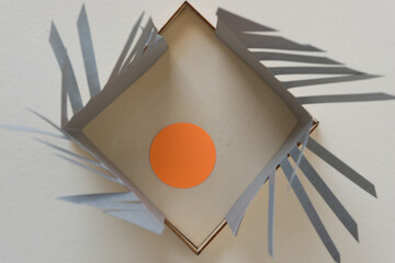 orange circle inside a box with 3d paper fringe