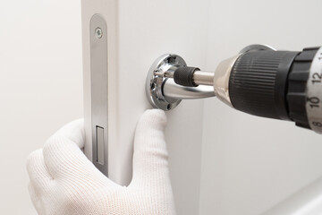 Man hands installing magnetic lock and door handle on  interior door using a screwdriver.