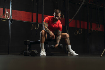 Chico musculoso con camiseta roja practicando deporte en un gym