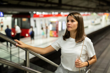 Young modern woman moving on subway station escalator