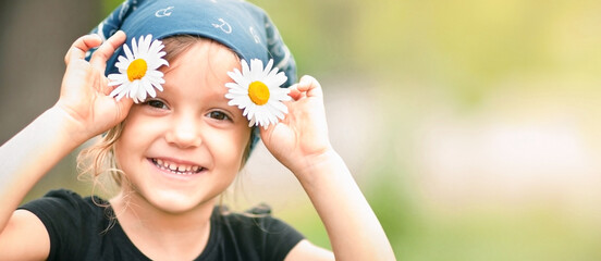a girl smiling at the camera with daisies in her hands
