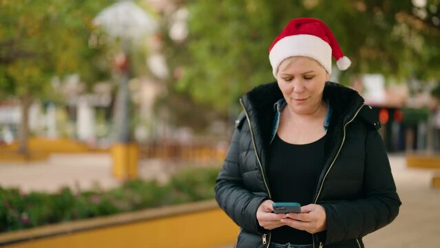 Mother and son holding christmas gift using smartphone at park