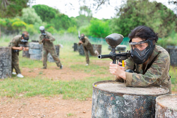 Fototapeta premium Group of people in full gear playing paintball on shooting range
