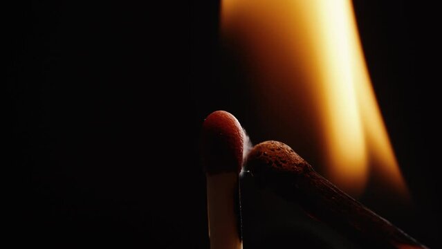 Wooden matchstick burning in darkness