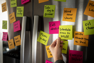 Hand Adding Schedule Time to Relax Sticky Note Memo to Fridge Door Full of Colorful Reminders