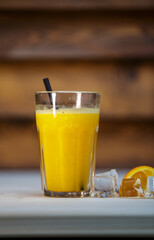 Fresh orange juice with crushed ice and straw on table with wood background