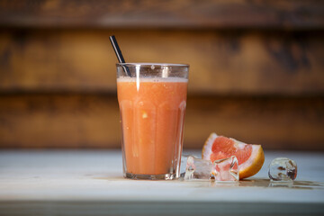 Fresh blood orange juice with crushed ice and straw on table with wood background