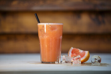 Fresh blood orange juice with crushed ice and straw on table with wood background