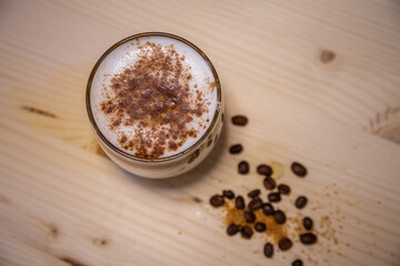 Layered coffee with cinamon in short glass from above on table with wood background and coffee beans