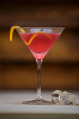 Fresh cosmopolitan martini in detail with lemon twist on table with wood background - obrazy, fototapety, plakaty
