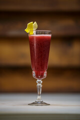 Fresh cold berries cocktail and crushed ice and lemon twist on table with wood background
