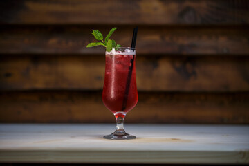 Fresh cold pomegranate cocktail with mint and crushed ice on table with wood background