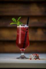 Fresh cold pomegranate cocktail with mint and crushed ice on table with wood background