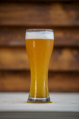 Fresh tall grass of beer on table with wood background