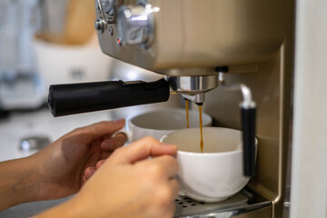 Female hands holding two white porcelain cups cooking fragrance aroma morning coffee in machine
