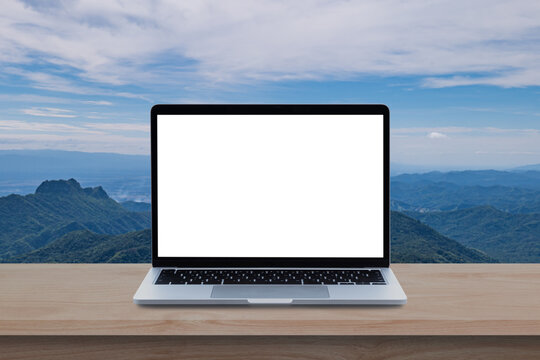 Modern Laptop computer with blank screen on wood table over mountain and sky background. © banphote