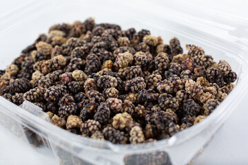 A closeup view of a container of dried black mulberries.