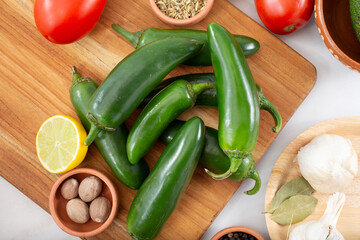 A top down view of several jalapeño chiles, among other salsa ingredients.